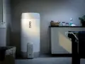 En OSO smart varmvattenberedare står i ett tvättstuga. Bredvid finns en tvättkorg och en torkställning med kläder.