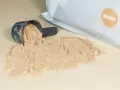 Moccha-smakande proteinpulver spillt från en skopa, med påsen i bakgrunden. Perfekt för att hålla koll på proteinpulver kcal.