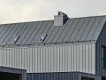 Nowoczesny dach z blachy na rąbek. Sprawdź blacha na rąbek cena m2, by poznać koszty pokrycia. Dwa okna dachowe i komin.