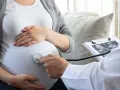 Lekarz osłuchuje brzuch ciężarnej, analizując wyniki badań USG. W trosce o zdrowie dziecka, wyklucza się m.in. cytomegalię.