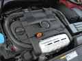 Silnik 1.4 TSI z widocznym logo VW. Widoczne elementy to m.in. pokrywa silnika, przewody, zbiornik płynu i filtr oleju.