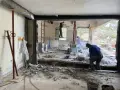 Travaux de démolition en cours pour une aide à la rénovation maison ancienne. Des ouvriers utilisent des outils pour casser le béton.