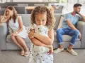 Ein Kind umklammert sein Stofftier, während die Eltern im Hintergrund getrennt sitzen. Ein Bild, das die emotionale Belastung eines Trennungsjahres mit Kindern widerspiegelt.