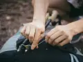 Ręce zapinają kijki trekkingowe do plecaka. Prosty sposób, jak przypiąć kijki do plecaka, by były zawsze pod ręką.