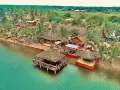 Rajskie wakacje w Ghanie: tropikalny kurort z palmami, plażą i domkami na wodzie.