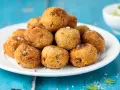 Pile di polpette tonno e ricotta dorate e croccanti, cosparse di sale grosso, su un piatto bianco.
