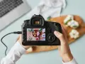 Dłonie trzymające aparat fotograficzny, na którego ekranie widać zdjęcie jedzenia.