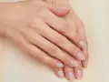 Mani curate, con unghie naturali e sane che sembrano respirare. La pelle è liscia e luminosa, poggiata su una superficie chiara.