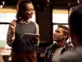 Camarera sonriente atiende a clientes de restaurante, tomando nota en una tablet.