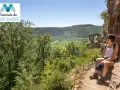 Une randonneuse profite de la vue sur la vallée verdoyante, vestige d'un château, lors de sa traversée du massif des Vosges, gr 53.