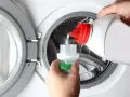 Versando detersivo liquido in un misurino per il prelavaggio lavatrice.