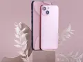 Dwa telefony, jeden ciemny, drugi różowy iPhone 11, stoją na kamiennych podstawkach, ozdobione delikatnymi, białymi gałązkami.