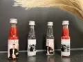 Vier kleine Flaschen mit personalisierten Etiketten, die Hochzeitsfotos und Namen zeigen. Perfekt als Schnaps zum selber machen für Gäste.