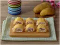 Sei rotoli di patate ripieni di prosciutto e formaggio cremoso, pronti per essere gustati.