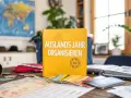 Ein Buch "Auslandsjahr organisieren" liegt auf einem Tisch mit Reisepässen, Karten und einer Kamera. Perfekt für die Planung des nächsten Abenteuers!
