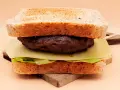 Burger z wołowiny, serem, sałatą i tostami na desce.