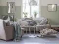 Vardagsrum i svensk stil med bekväm soffa, fåtölj och en sovande hund. Vårljus strömmar in genom fönstret och skapar en mysig atmosfär.