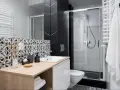 Élégante petite salle de bain italienne avec carrelage noir et blanc, douche moderne et meuble vasque en bois clair.