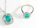 Conjunto de collar y anillo con una deslumbrante piedra de geminis turquesa rodeada de diamantes, sobre fondo blanco.