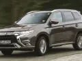 Brązowy Mitsubishi Outlander PHEV jedzie po drodze, zamazane tło sugeruje ruch.