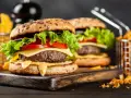Dwa soczyste hamburgery z serem, sałatą i pomidorem, podane z frytkami.