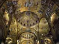 Interno dorato della Basilica di San Marco, con mosaici bizantini che adornano le volte e le cupole di San Marco, raffiguranti scene sacre e figure angeliche.