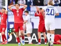 Piłkarze w czerwonych strojach, w tym jeden z numerem 17, wyrażają frustrację. Polska przegrywa mecz.