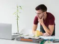 Joven autónomo reflexiona en su escritorio. Lo cotizado como autónomo cuenta para el paro, una tranquilidad para su futuro.