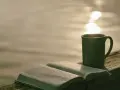 Offenes Buch mit Bibelversen, Tasse Kaffee am Seeufer. "Ich liebe den Herrn, denn er hört meine Stimme" (Psalm 116:11).