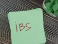 Na zielonej kartce napisano "IBS". Może to przypomnienie o lekach, takich jak Duspatalin, które pomagają w łagodzeniu objawów zespołu jelita drażliwego.