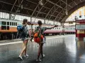 Dwie podróżniczki z plecakami idą wzdłuż peronu, gdzie stoi długi pociąg. Może to być ich pierwszy pociąg Eurostar.