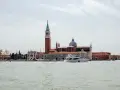 Un'isola di Venezia nascosta, con un campanile imponente, una chiesa con cupola e uno yacht che solca le acque.