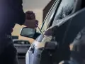 Tentativo di furto d'auto: un uomo usa un cacciavite per forzare la portiera, un'azione che rientra nella verifica veicoli rubati.