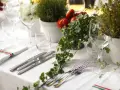 Elegancko nakryty stół na wesele, z kieliszkami, sztućcami i ozdobami z pomidorków i bluszczu. Idealne miejsce na wino na wesele.