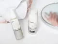 Białe opakowania kosmetyków Lynia: Face Booster i Face Cream, z widocznym składnikiem papaina. Obok ręczniki i lustro.