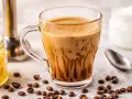 Kawa bullet coffee w szklance, obok ziarna kawy, słoiczek z miodem i łyżeczka.