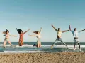 Fünf junge Leute springen ausgelassen am Strand. Sie freuen sich über ihr Sprachreise Stipendium und die Freiheit.