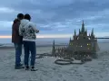 Para podziwia imponujące zamki z piasku na plaży, w okolicach Kołobrzegu. Wieczorne światła dodają magii.