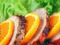 Rebanadas de solomillo a la naranja, con hierbas y rodajas de naranja fresca, acompañadas de lechuga verde.