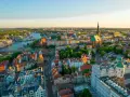 Widok z lotu ptaka na Szczecin z rzeką, zabytkowymi kamienicami i kościołami w złotym świetle zachodzącego słońca.