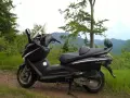Czarny skuter Sym GTS 125 na górskiej drodze. Jego prędkość maksymalna pozwala na odkrywanie malowniczych zakątków.