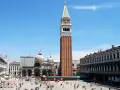 La maestosa altezza del campanile di San Marco domina Piazza San Marco, con la Basilica sullo sfondo e la folla che passeggia.