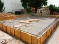 Drewniane szalunki i zbrojenie czekają na beton, tworząc fundamenty z kamienia.