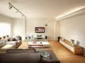Iluminar un salón moderno con luces de riel y lámpara de arco. Sofás grises, mesa de centro blanca y mueble de TV.
