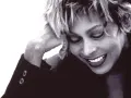Tina Turner lächelt mit geschlossenen Augen, die Hand am Kopf. Ein ikonisches Bild der Musiklegende.