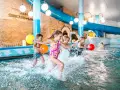 Dzieci bawią się w basenie, rzucając kolorowymi piłkami. Idealne miejsce na rodzinny wypoczynek - hotel z basenem dla dzieci Podlaskie.