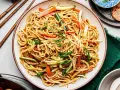Pyszny makaron chow mein z warzywami i sezamem, gotowy do jedzenia pałeczkami.