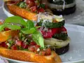 Vegane Grillrezepte: Bruschetta mit Tomaten und gegrilltem Gemüse-Turm, garniert mit Basilikum und Parmesan.