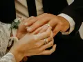 Dłoń panny młodej zakłada obrączkę na palec pana młodego. To ważny moment, jak pytania przed ślubem, symbolizujący miłość i przyszłość.