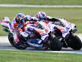 Dos pilotos de MotoGP compiten en una carrera emocionante. El piloto número 6, con casco rojo y blanco, lidera, seguido de cerca por el número 88.